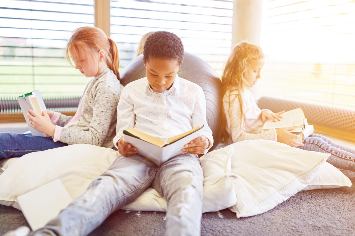 Group of kids are reading in reading corner of a library